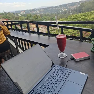 open laptop on a table with drink on an outside balcony