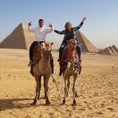 woman and young man riding camels at the egyptian pyramids
